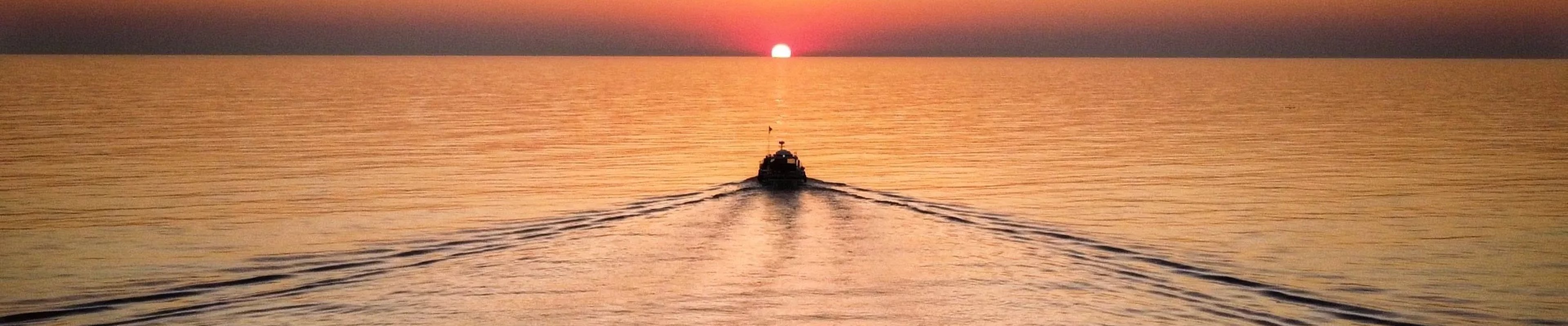 Barco navegando sobre el mar bajo un cielo de tonos dorados