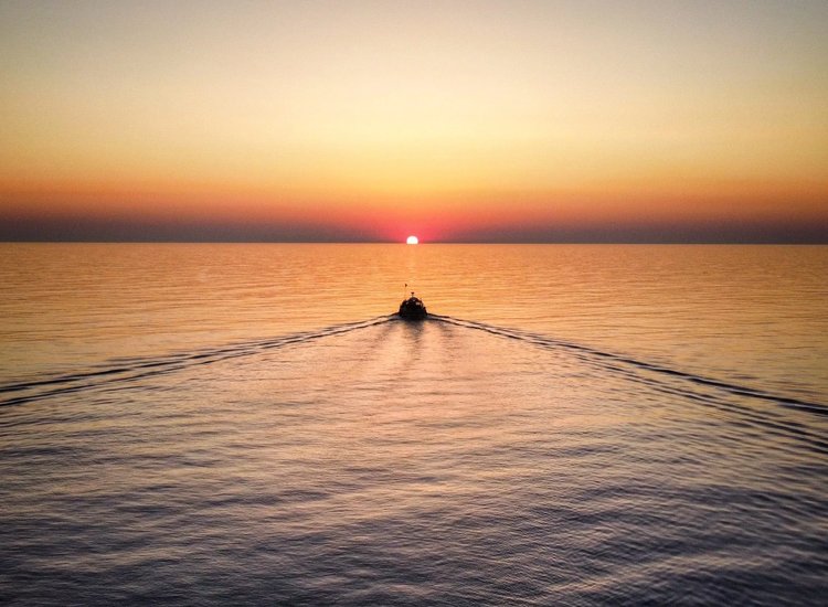 Barco navegando sobre el mar bajo un cielo de tonos dorados