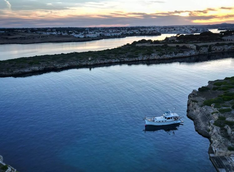 Llaut fondeado junto a la costa de Menorca al atardecer